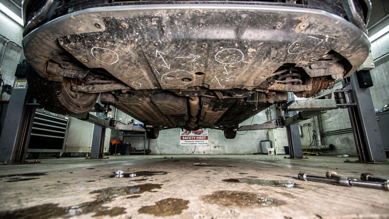 Underside of a used Skoda Octavia raised on a lift with three marked defect areas